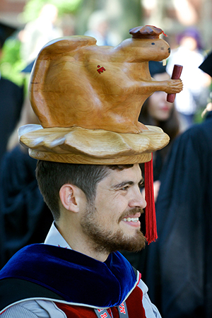 MIT doctoral graudation photo showing Dr. Rojas with the his carved wood beaver head.  The hat is made out of two parts.  An oak platform carved into the graduation hat and a beaver carved out of cherry holding a diploma.